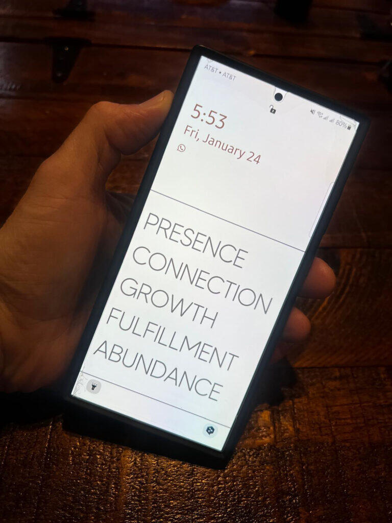 A cellphone screen with a background that reads, Presence, Connection, Growth Fulfillment, Abundance.